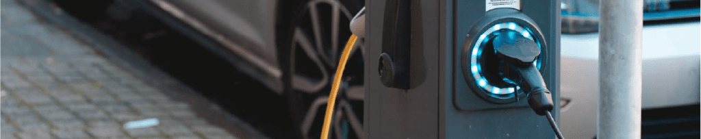 EV charging station with silver car behind it.